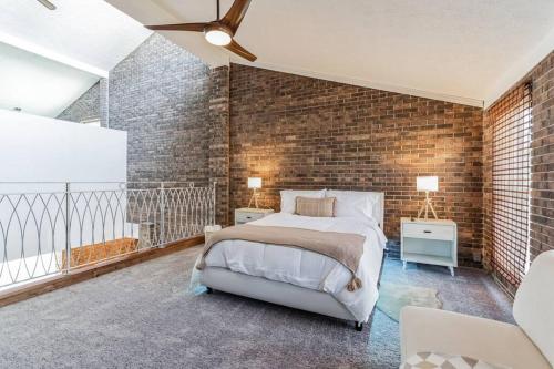 Un dormitorio con una pared de ladrillo y una cama en Beltline Beauty*Mins to Benz Stadium, Game Room*, en Atlanta