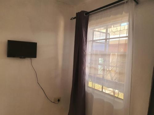 ein Fenster mit einem Vorhang und einem TV an der Wand in der Unterkunft Faraja in Meru