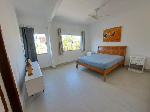 a bedroom with a bed and a table and two windows at Linda cobertura Prainha de Mambucaba Paraty 50m da praia in Paraty