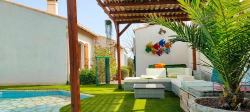 un patio al aire libre con sofá y piscina en Divine ROUJAN Sunny Lodge, en Roujan