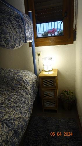1 dormitorio con cama y mesita de noche con ventana en Casa Nieves -La buardilla del cielo, en Villahermosa del Río