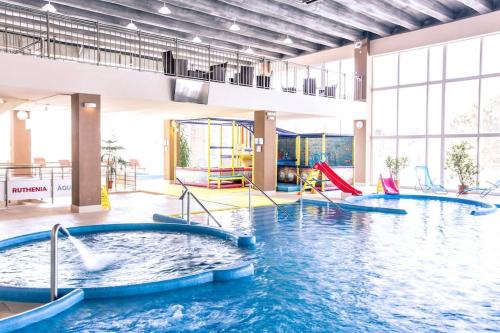 a large indoor pool with slides in a building at Usadlosť pri lúke in Mlynárovce