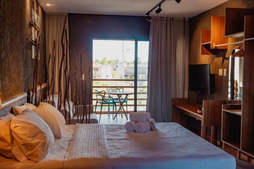 a bedroom with a bed and a balcony with a table at Condomínio Gamboa Patacho a 190 da praia na Rota dos Milagres in Pôrto de Pedras