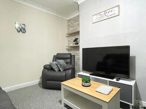 - un salon avec une télévision à écran plat et une chaise dans l'établissement Cosy home, family & contractor friendly 4 bedroom near Leeds centre, sleeps 7, à Leeds