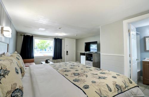 um quarto com uma cama grande e uma televisão em Windrift Motel em West Yarmouth