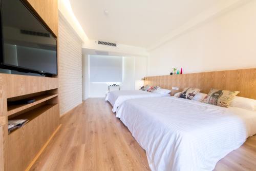 a bedroom with two beds and a flat screen tv at Zi Jing Cheng B&B in Hualien City