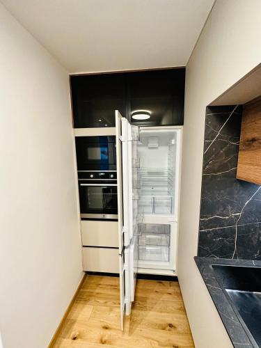 an empty refrigerator with its door open in a kitchen at Apartman Aurora Self Check in in Zagreb