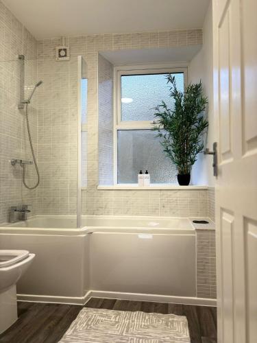 a bathroom with a tub and a toilet and a window at Cardiff/Pernath Home2 in Cardiff