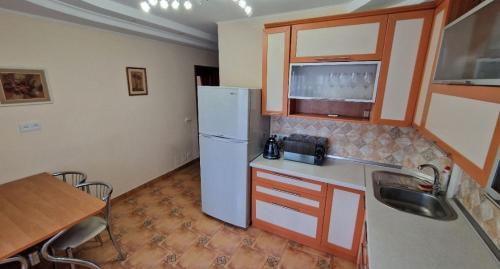 La cuisine est équipée d'un réfrigérateur blanc et d'un évier. dans l'établissement Уютные апартаменты, à Chişinău