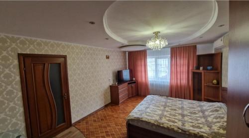 ein Schlafzimmer mit einem Bett und einem TV in der Unterkunft Уютные апартаменты in Chişinău