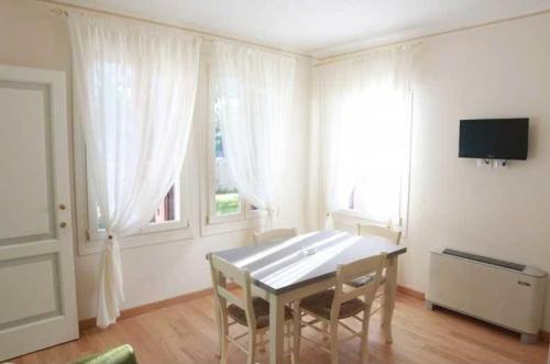 a dining room with a table and two windows at Villa delle Rose in Portogruaro