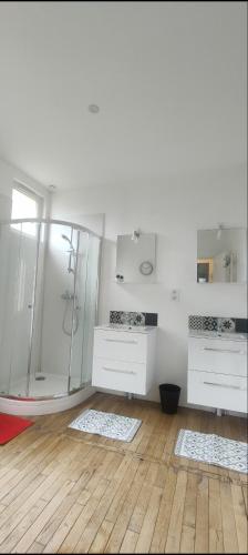 La salle de bains blanche est pourvue d'une douche et de 2 lavabos. dans l'établissement Appartement entier deux chambres, à Saint-Nazaire