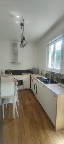 une cuisine avec des armoires blanches, une table et un évier dans l'établissement Appartement entier deux chambres, à Saint-Nazaire