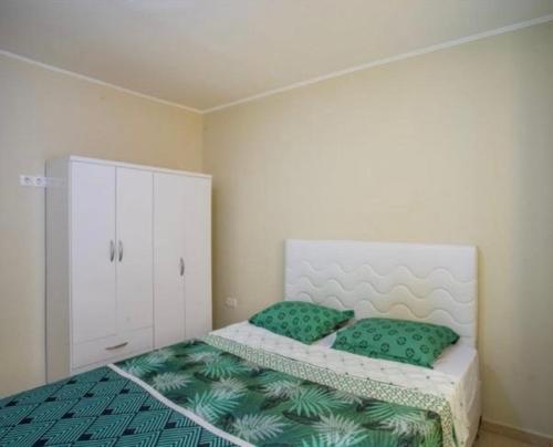 a bedroom with a bed with two green pillows at Two Bedroom app Villa Islandessa in Willemstad