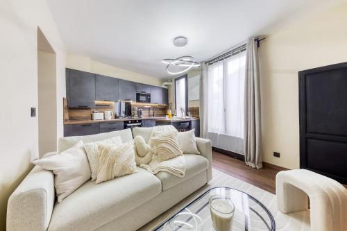 un salon avec un canapé blanc et une cuisine dans l'établissement Le splendide (Chic & Chaleureux), à Vincennes