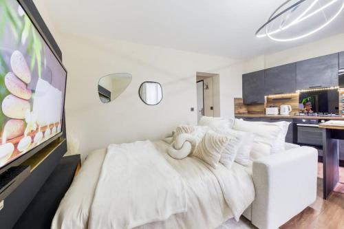 um quarto com uma cama branca e uma cozinha em Le splendide (Chic & Chaleureux) em Vincennes