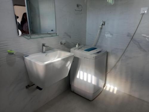 Baño blanco con lavabo y espejo en Chamara home stay, en Ratgama Hegoda