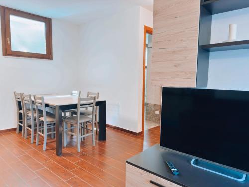 a dining room with a table and a flat screen tv at Finestra su Villalago in Villalago