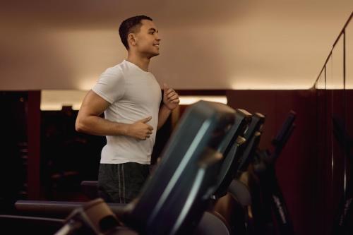a man is running on a treadmill in a gym at Hotel Cafe Royal in London