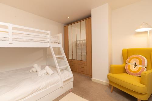 a bedroom with a bunk bed and a yellow chair at Central Gem: Cosy 2BR with Private Balcony in Manchester