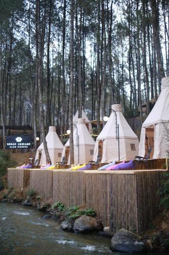 a group of tents are lined up next to a river at Regan Luxcamp by Digihub Hospitality in Palayangan