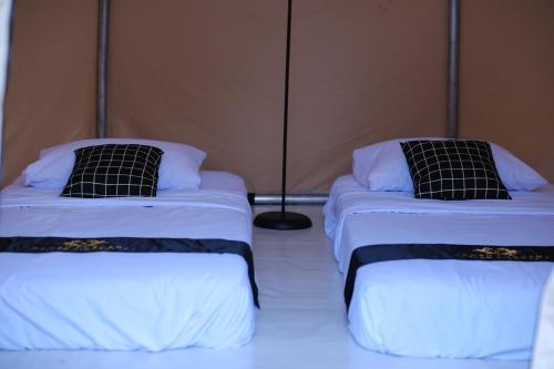 two beds with black and white pillows in a room at Regan Luxcamp by Digihub Hospitality in Palayangan