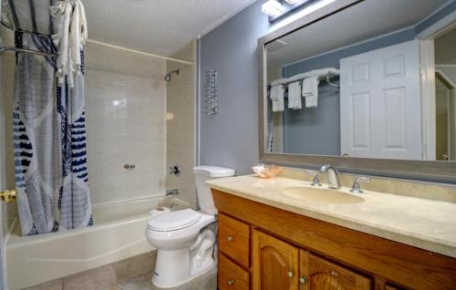 uma casa de banho com um lavatório, um WC e um espelho. em Windrift Motel em West Yarmouth