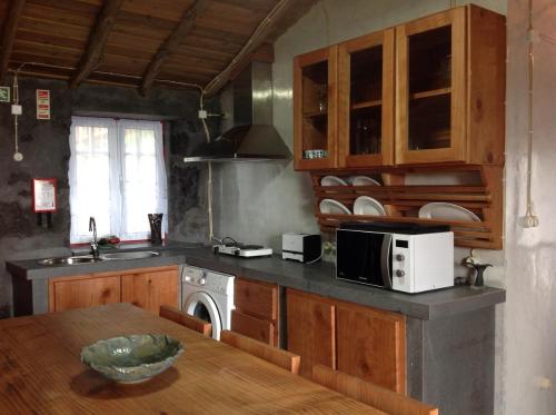 a kitchen with a table and a microwave oven at Aldeia Dos Caldeirões in São Mateus