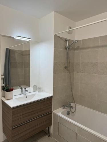 une salle de bain avec un lavabo, une baignoire et un miroir dans l'établissement Appartement Cosy proche Paris, à Noisy-le-Sec