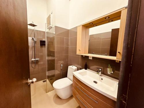 a bathroom with a toilet and a sink and a mirror at Grand Sri Lounge - Ocean Breeze Hotel residents in Negombo
