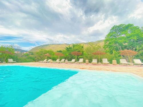 - une piscine dans un complexe avec des chaises et des parasols dans l'établissement Trip Monkey del Río, à San Gil