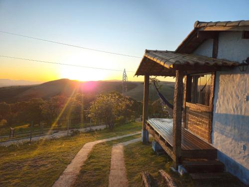 a bench next to a building with the sunset in the background at Chalés Vila Real in Carrancas