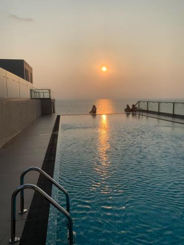 a swimming pool with a sunset in the background at Grand Sri Lounge - Ocean Breeze Hotel residents in Negombo