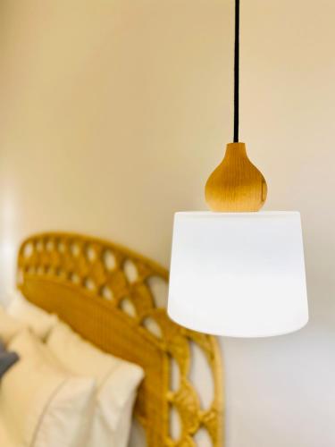 a lamp with a white shade next to a bed at Gerani Deluxe Houses in Astypalaia Town