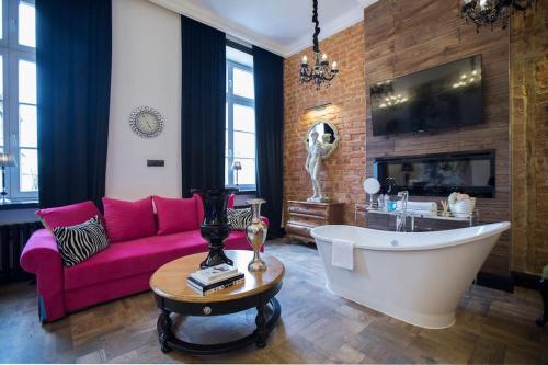 a living room with a pink couch and a tub at Luksus Apartamenty - Mariacka in Szczecin