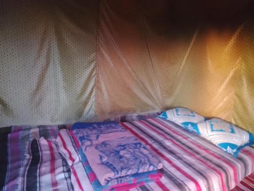 un montón de mantas sentadas junto a una cortina en M'Hamid Budget Lodge en Mhamid