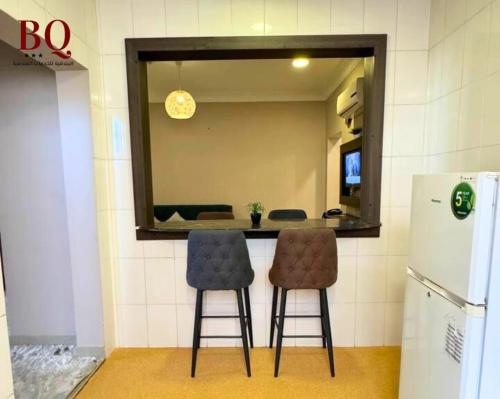 a kitchen with two bar stools and a mirror at البندقية للخدمات الفندقية BQ HOTEL SUITES in Buraydah