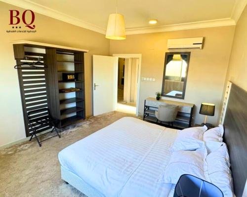 a bedroom with a large white bed and a desk at البندقية للخدمات الفندقية BQ HOTEL SUITES in Buraydah