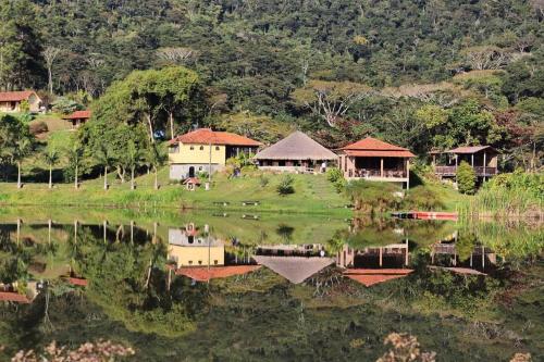 a group of houses on a hill next to a lake at Hotel Fazenda Upã Moña in Vassouras