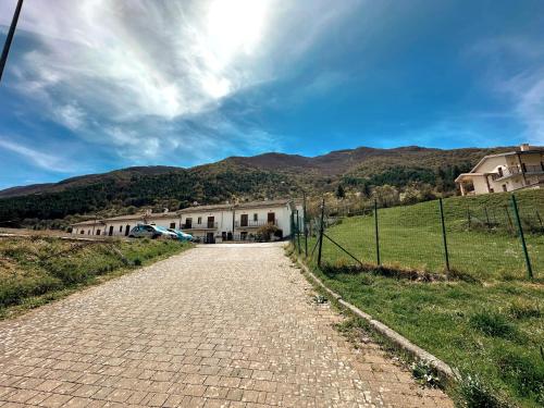 a cobblestone road in a field with houses and mountains at Finestra su Villalago in Villalago
