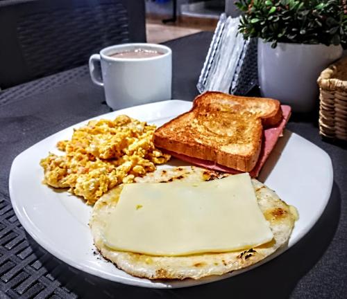 un piatto di prodotti per la colazione con uova e pane tostato e una tazza di caffè di Hotel Ruiseñor Itagui a Itagüí