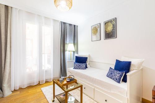 een witte kamer met een stoel bij het raam met blauwe kussens bij Maison élégante 15 minutes de paris in Arcueil