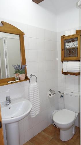 a white bathroom with a toilet and a sink at El Refugio de Casa Nieves in Villahermosa del Río