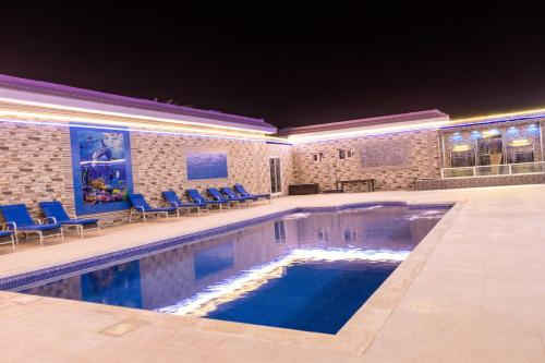 una gran piscina con sillas azules alrededor. en Andalusia farm en Al Rahba