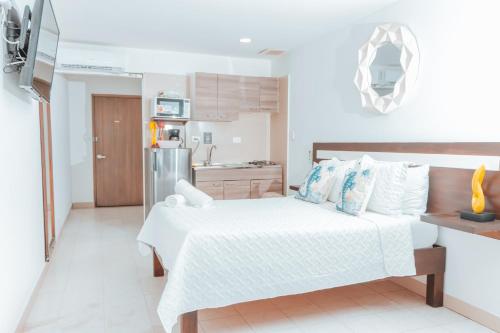 a white bedroom with a bed and a kitchen at APARTAHOTEL BEIRUT INN in San Andrés