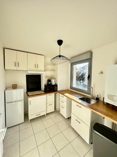 eine Küche mit weißen Schränken, einer Spüle und einer Mikrowelle in der Unterkunft Superbe appartement Paris/Bagnolet 203 in Bagnolet
