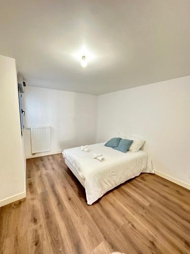 a white bedroom with a bed and a wooden floor at Superbe appartement Paris/Bagnolet 203 in Bagnolet