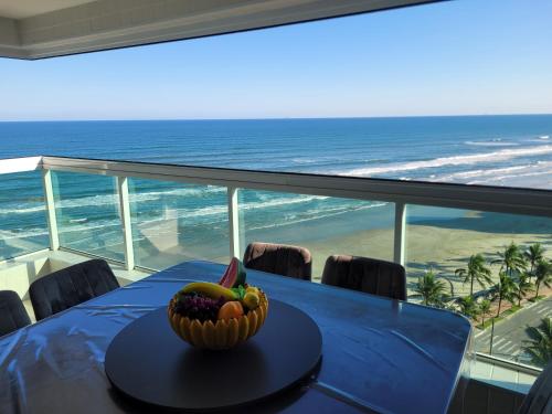 a table with a bowl of fruit on top of the ocean at Condomínio Firenze in Mongaguá