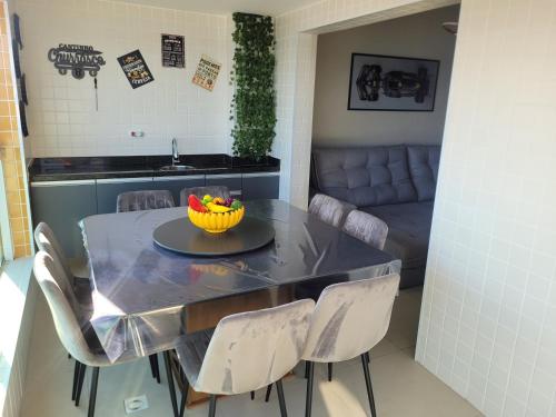 einen Esstisch mit Stühlen und eine Obstschale darauf in der Unterkunft Condomínio Firenze in Mongaguá