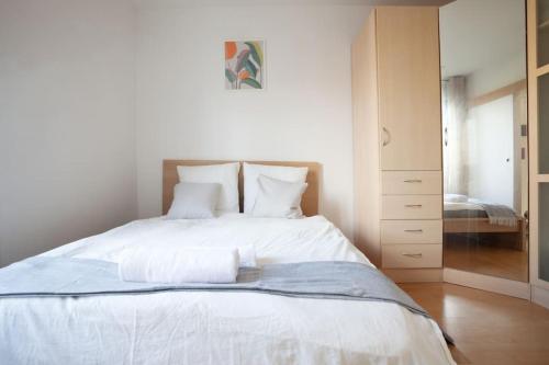 Schlafzimmer mit einem Bett mit weißer Bettwäsche und einem Spiegel in der Unterkunft 2 pièces Cosy - proche RER A - proche Paris in Houilles